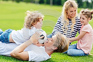 happy family with two kids having fun with soccer ball while lying