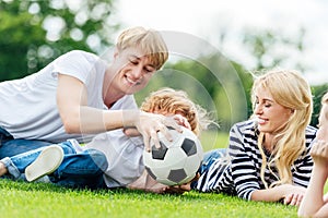 happy family with two kids having fun with soccer ball while lying