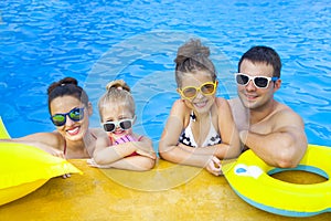 Happy family with two kids having fun in the swimming pool