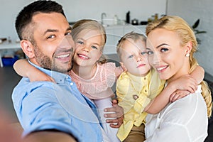 happy family with two kids hugging and smiling at camera