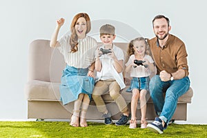 happy family with two kids sitting on couch and playing