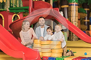 happy family with two kids smiling at camera while playing together in entertainment