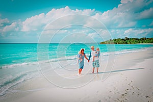 Happy family with two kids walk on tropical beach