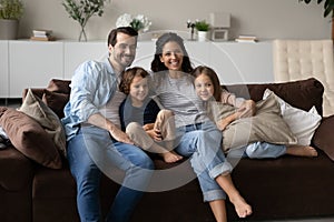 Happy family with two little kids sitting on comfortable couch