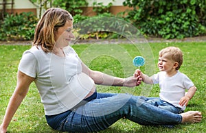 Happy family of two: little toddler boy and his young pregnant m