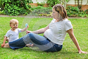 Happy family of two: little toddler boy and his young pregnant m