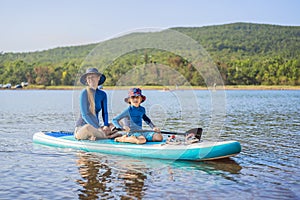 happy family of two, mother and son, enjoying stand up paddling during summer vacation