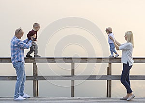 Happy family of two parents and children, one boys, baby girl, have good time on the river jetty. Sunset.