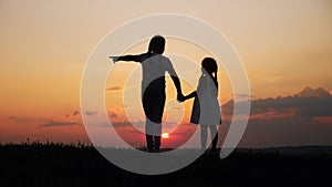 Happy family two sisters walks at sunset in the park silhouette. two daughters hold hands outdoors. kid dream concept