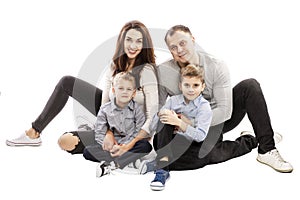 Happy family with two sons are sitting on the floor. Isolated over white background