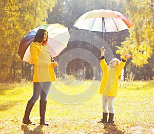 Happy family with umbrellas in sunny autumn rainy day