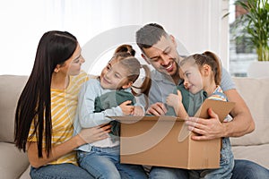 Happy family unpacking moving box at their new house