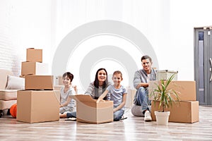 Happy family unpacking moving boxes at their home