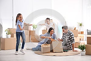 Happy family unpacking moving boxes at their home