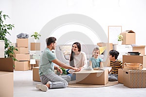 Happy family unpacking moving boxes at their home