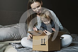 Happy family unwrapping big cardboard box delivered to their house. Online shopping and delivery from international retailers