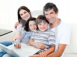 Happy family using a laptop sitting on sofa