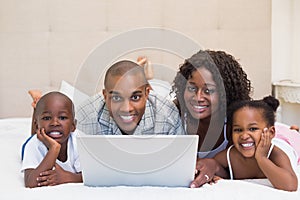 Happy family using laptop together on bed