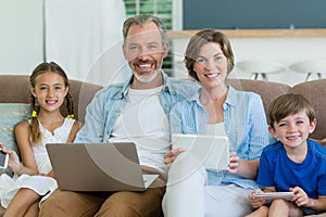 Happy family using mobile phone, digital tablet and laptop in living room