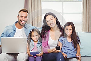 Happy family using modern technologies while sitting on sofa