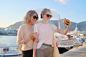 Happy family on vacation, mom and teenage daughter taking selfie on smartphone