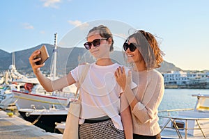 Happy family on vacation, mom and teenage daughter taking selfie on smartphone