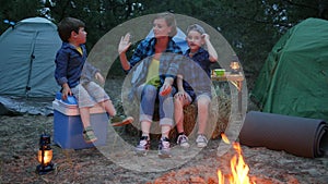 Happy family on vacation outdoors, mother and two children sitting around on straw bale beside balefire, mom and kids