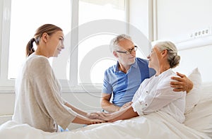 Happy family visiting senior woman at hospital