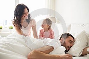 Happy family waking up in bed at home