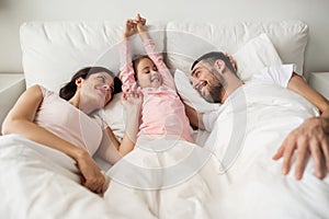 Happy family waking up in bed at home photo