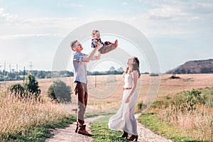 Happy family on a walk in the field.  Father toss up his son