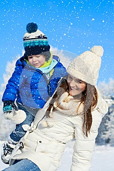 Happy family on the walk in sunny, winter day - snow falling