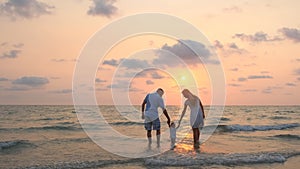 Happy family walking along the sea coast at sunset.