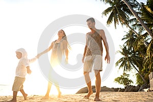 Happy family walking on the beach at sunset