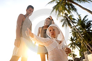 Happy family walking on the beach at sunset