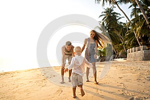 Happy family walking on the beach at sunset