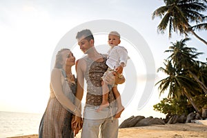 Happy family walking on the beach at sunset