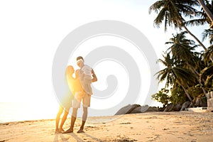 Happy family walking on the beach at sunset