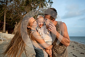 Happy family walking on the beach at sunset