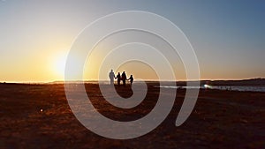 Happy family walking on coast bay. Family walking on sea coast. Silhouettes sunset