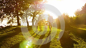 Happy family walking near the sea. Field and trees in countryside. Warm colors of sunset or sunrise. Loving parents and