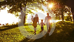 Happy family walking near the sea. Field and trees in countryside. Warm colors of sunset or sunrise. Loving parents and