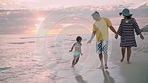 Happy family walking on ocean coast. Silhouettes sunset.