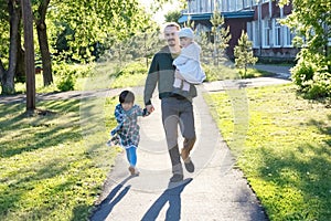 Happy family walking in park. father with two daughters at sunny day. dad with two little kids talking in park outdoor