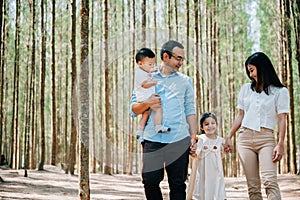 Happy family walking through the sunny forest