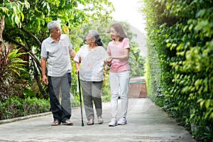 Happy family walking together in the garden. Old elderly using a walking stick to help walk balance. Concept of  Love and care of