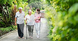 Happy family walking together in the garden. Old elderly using a walking stick to help walk balance. Concept of  Love and care of