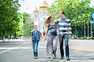 Happy family walking together. Pregnant mother, father and son spend time on city street