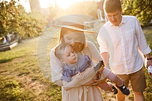 Happy family is walking togther in garden. Mother is playing with her son and carring him on hands. She is smiling photo