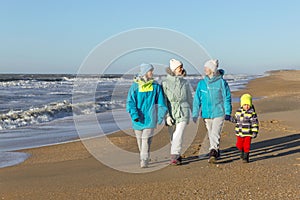 A happy family walks along the sandy seashore in winter. Laughing mother, grandmother and children. Love and tenderness